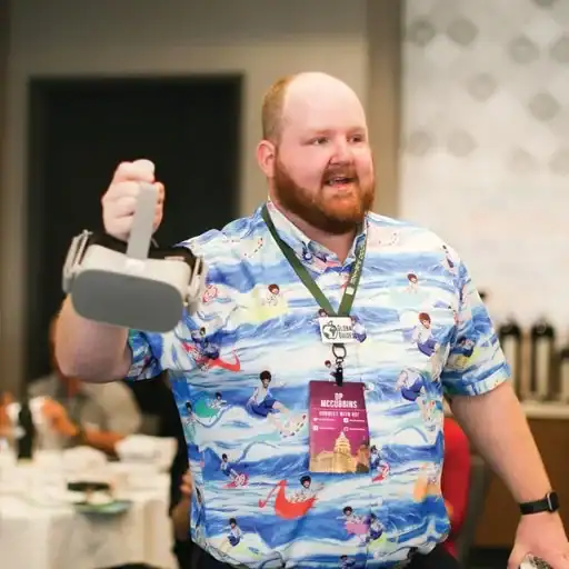 A candid photo of Dr. O.P. McCubbins smiling and speaking at an educational conference while holding up a virtual reality headset to show the audience.
