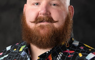 : ⁠Official professional headshot portrait of Dr. O.P. McCubbins smiling, wearing a dark patterned button-down shirt against a clean, neutral background.⁠