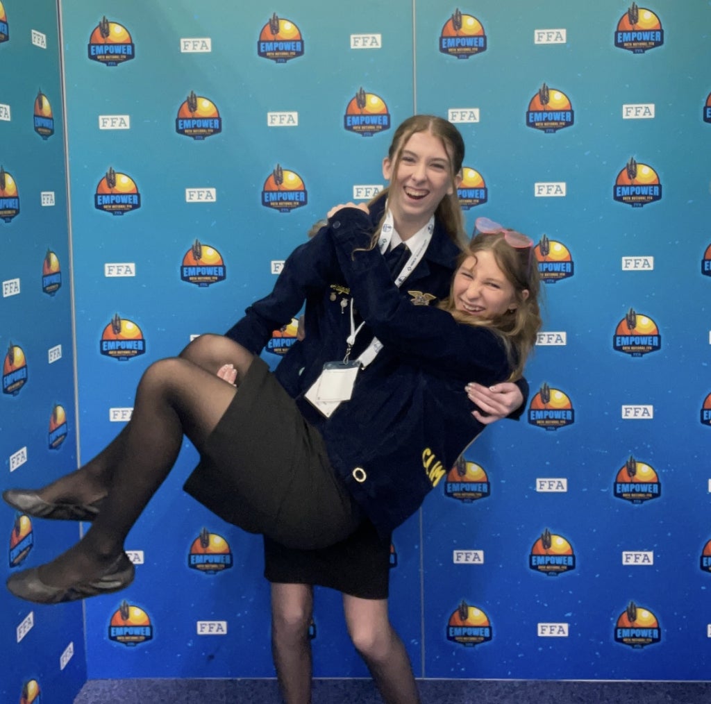 Abigail Morgan (standing) and Khloe Durham (being held) in a photo booth at the 98th National FFA Convention.
