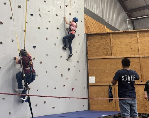 Two members giving it a go on the camp rock wall.