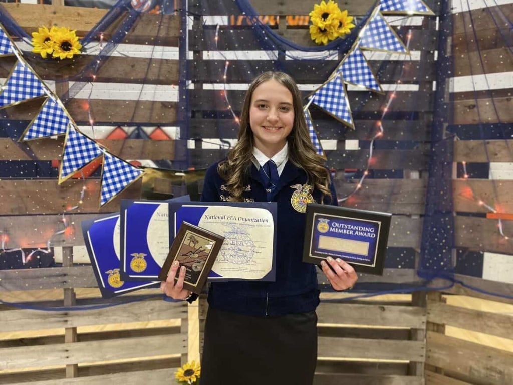 Grace Schmidt holding awards at her final chapter banquet.