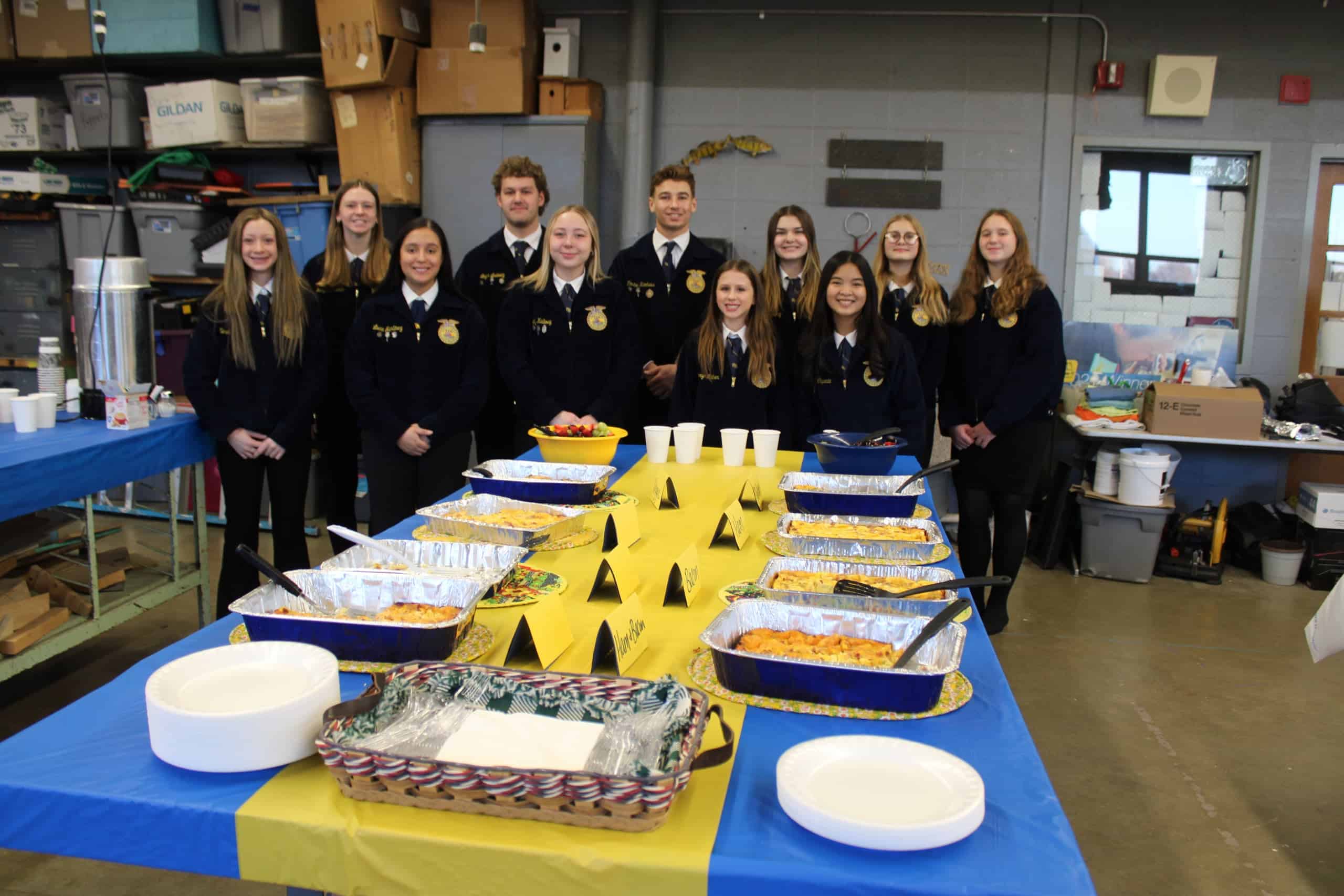 FFA members stand in front of a table with a buffet of food with blue and gold table cloth