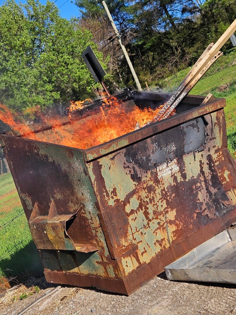 Flames burn inside a metal dumpster during a live fire training demonstration before SoyFoam is applied.