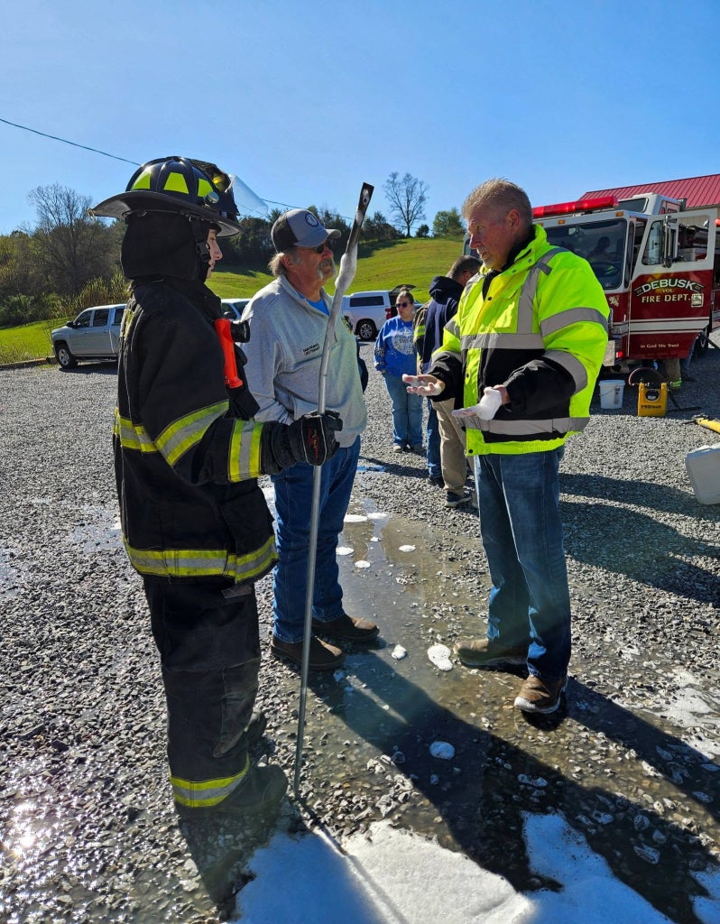 Dakine Thompson, retired Greeneville Fire Department Lt. Sam Reaves and Jeff King discuss SoyFoam during a live fire demonstration at Debusk Volunteer Fire Department.
