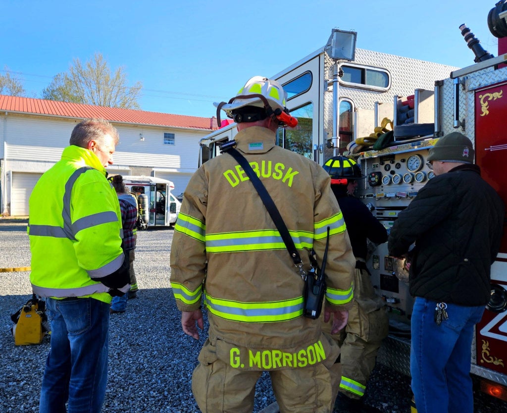 Jeff King, Gary Morrison and other attendees gather beside a Debusk Volunteer Fire Department engine during the SoyFoam demonstration.